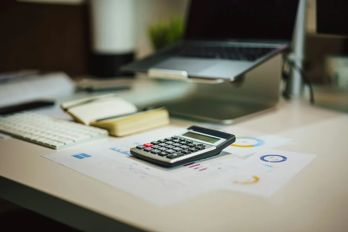 A desk with a calculator and printed reports