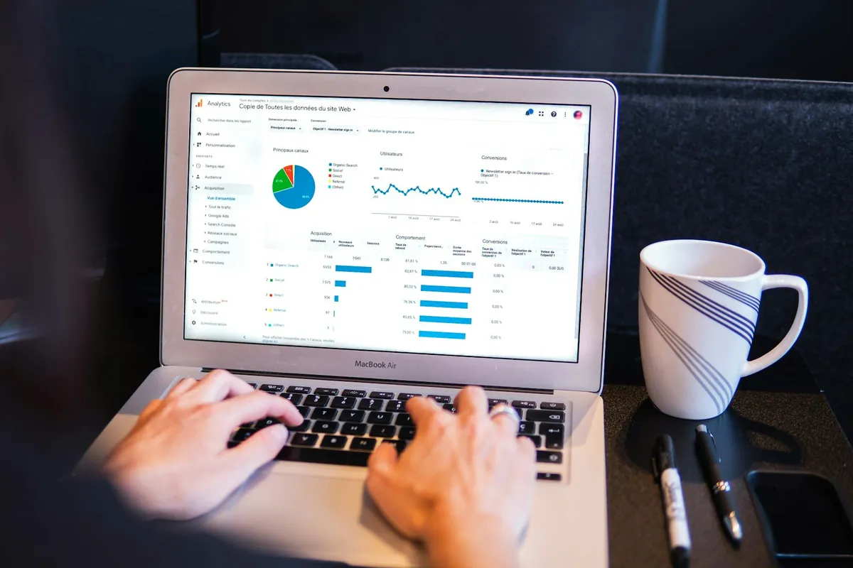 A laptop showing a dashboard beside a coffee mug