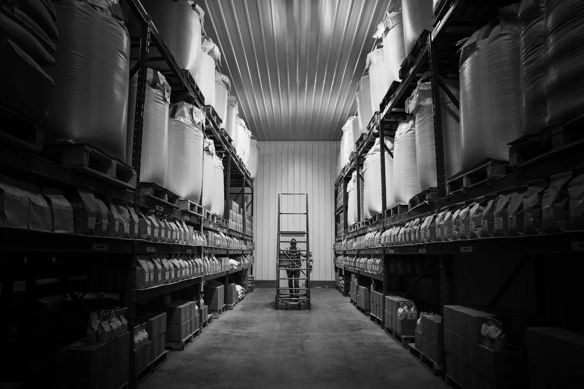 A warehouse aisle of shelved stock in black and white