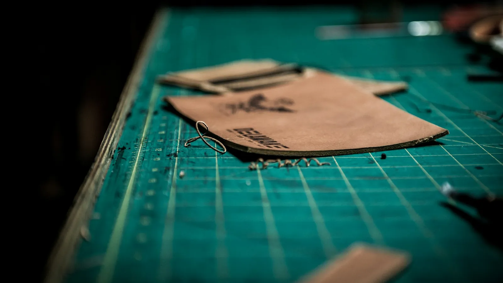 A leather worker cutting a pattern on a cutting mat