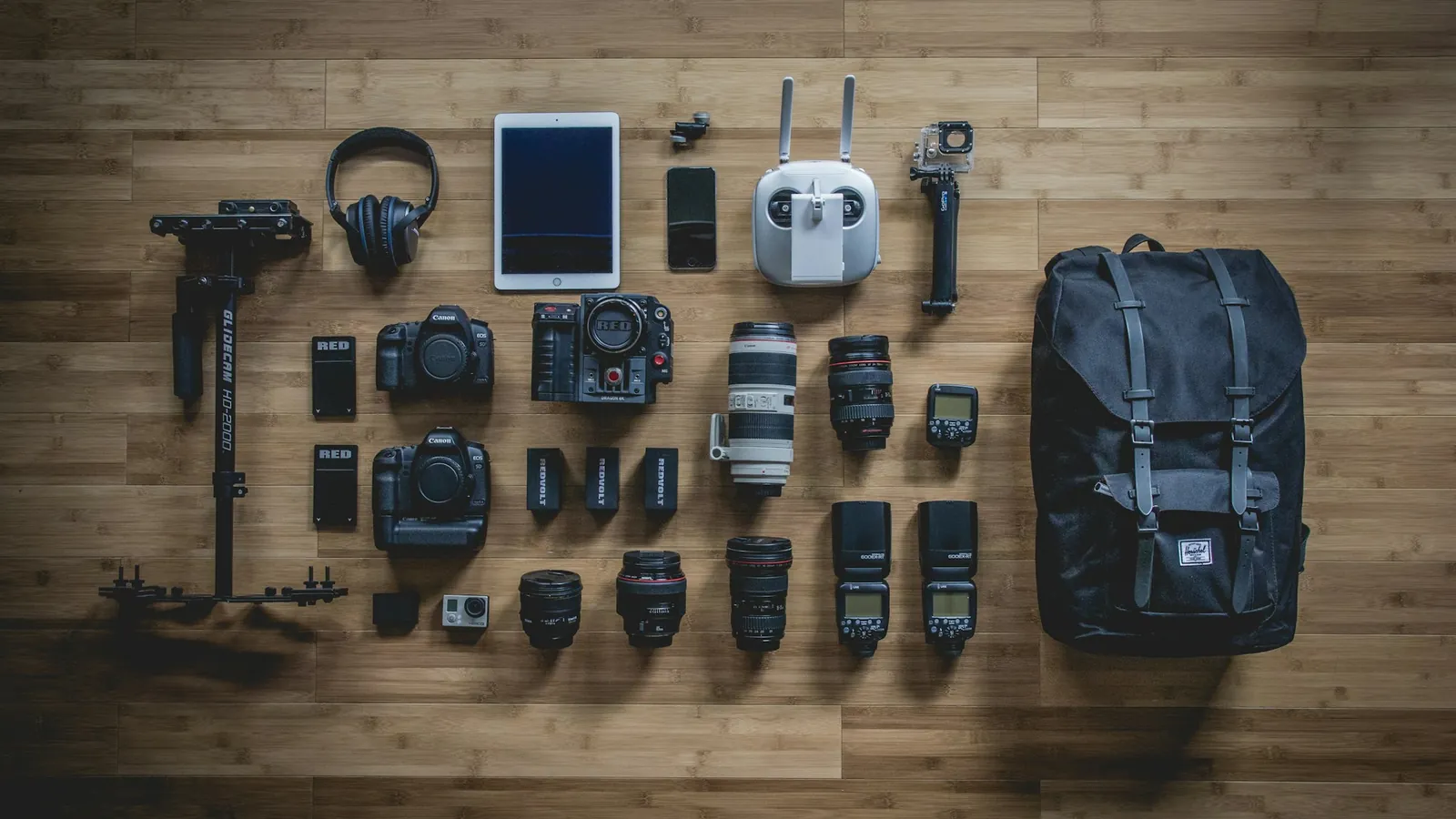 Camera and travel gear laid out on a wooden floor