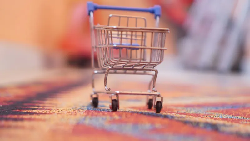 A miniature shopping trolley on a soft, colourful blurred background