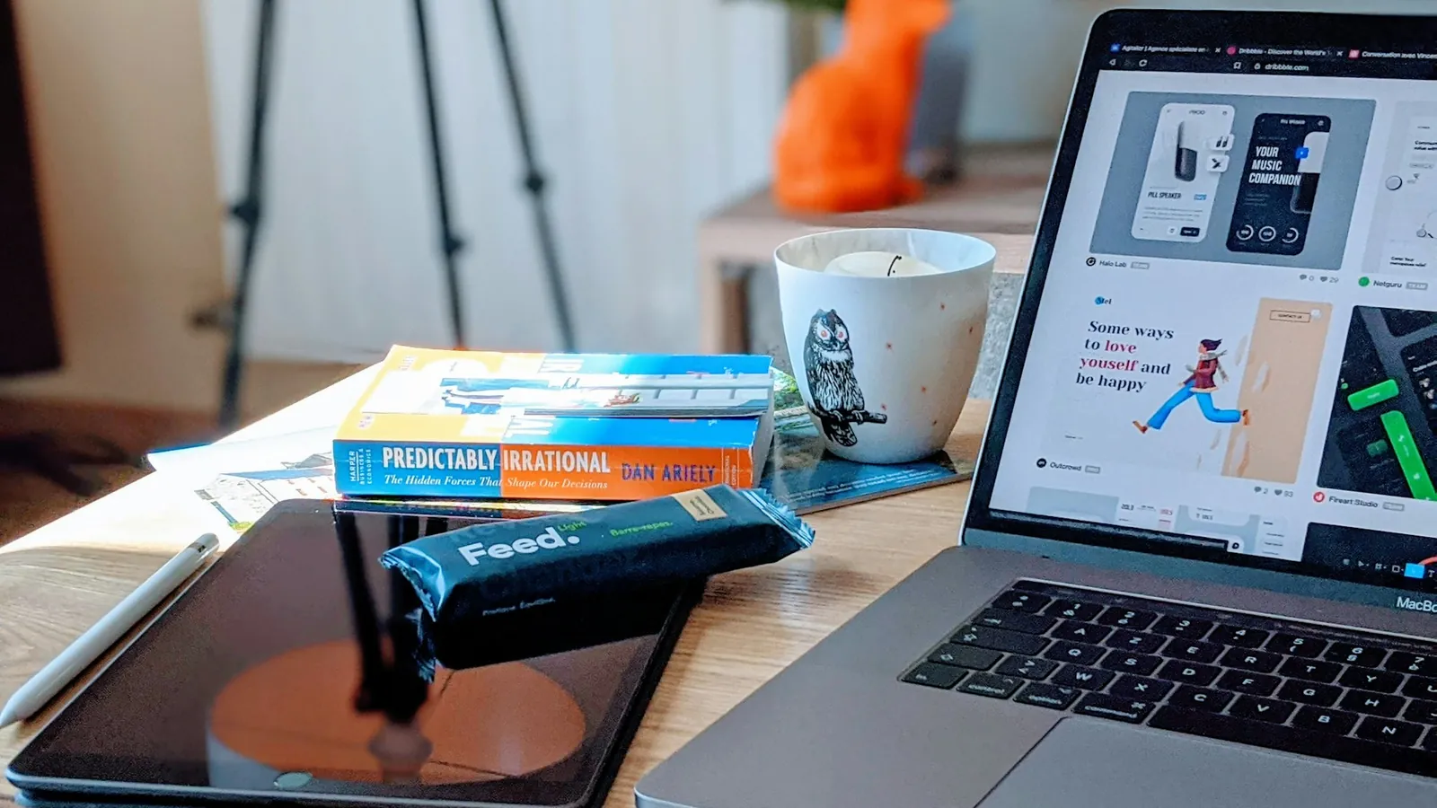 A laptop showing a design layout beside a tablet and books