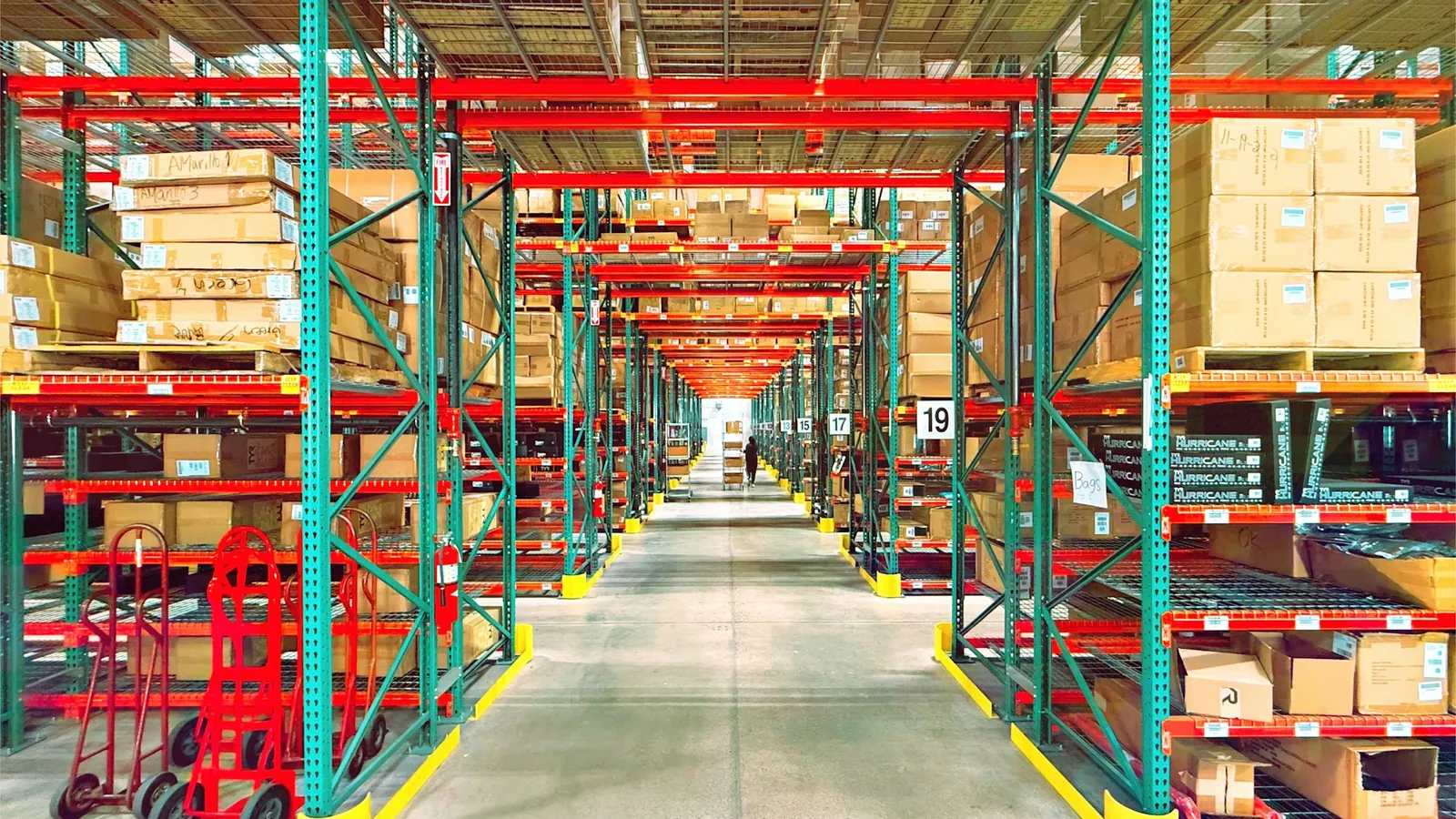 Red and green warehouse racking stocked with cartons