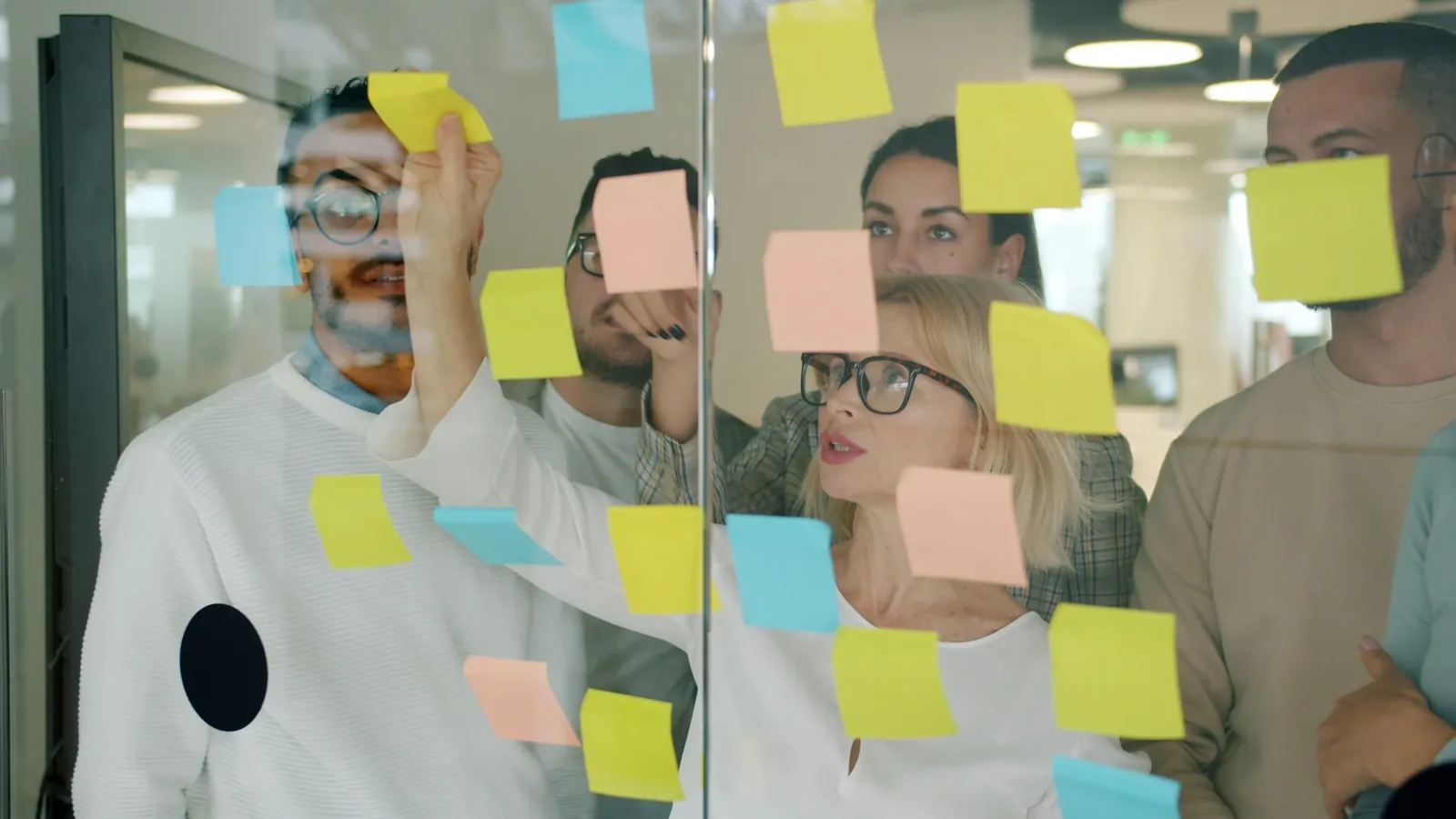 A team working through sticky notes on a glass wall