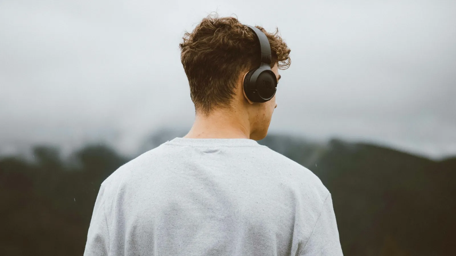 A man wearing headphones looking out over hills