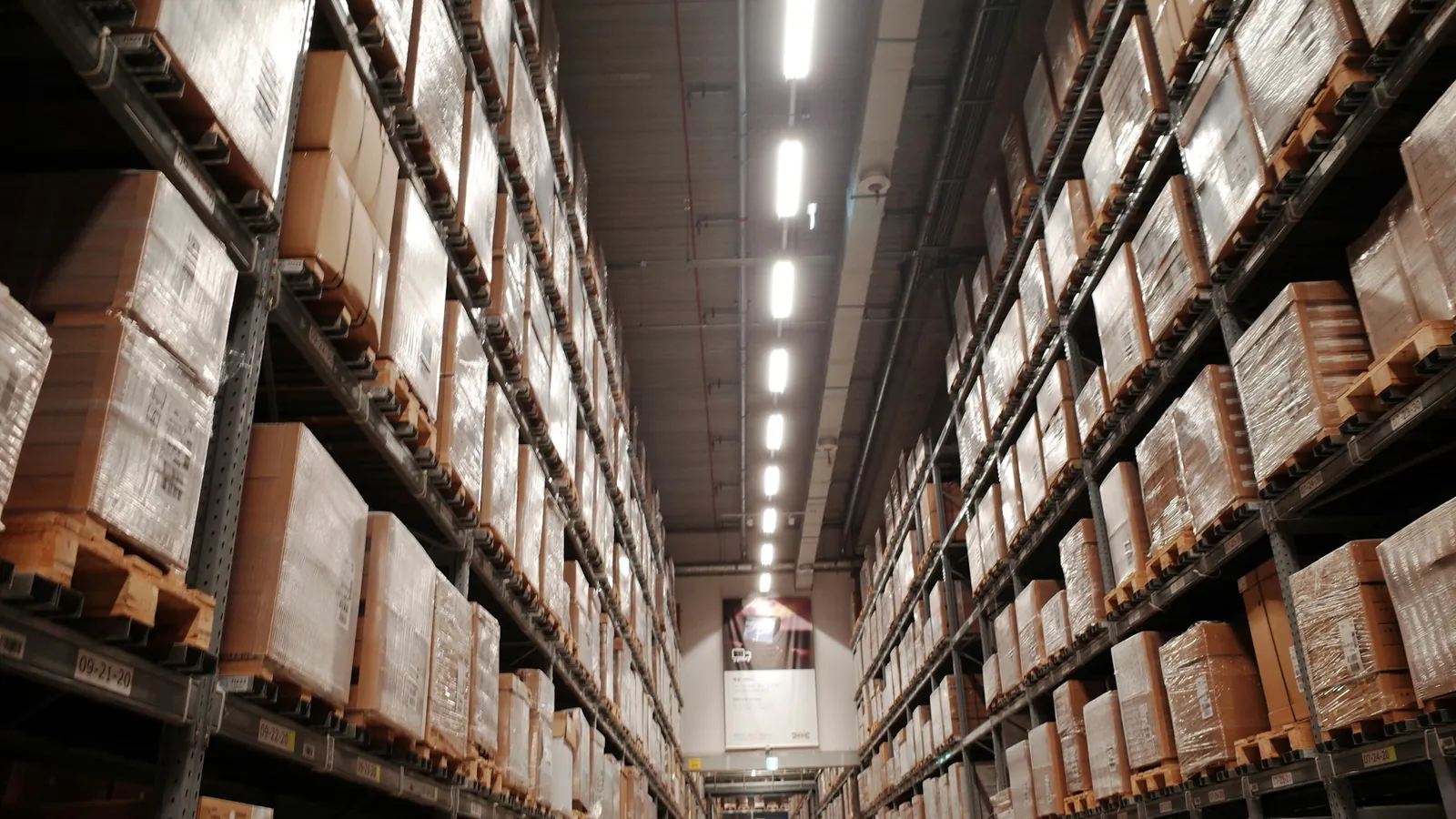 A long warehouse aisle of shelved cartons