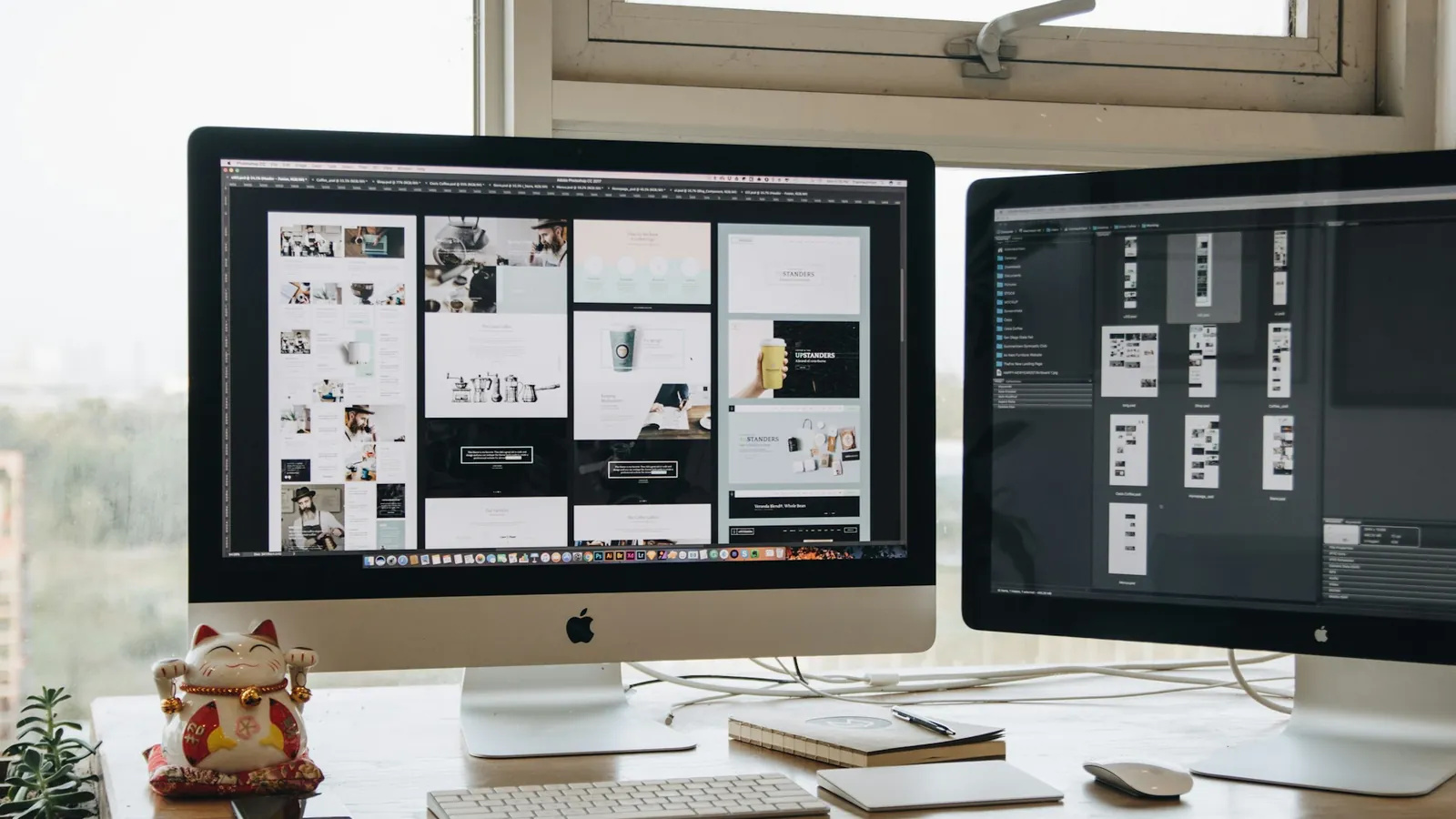Two monitors showing web page designs on a desk