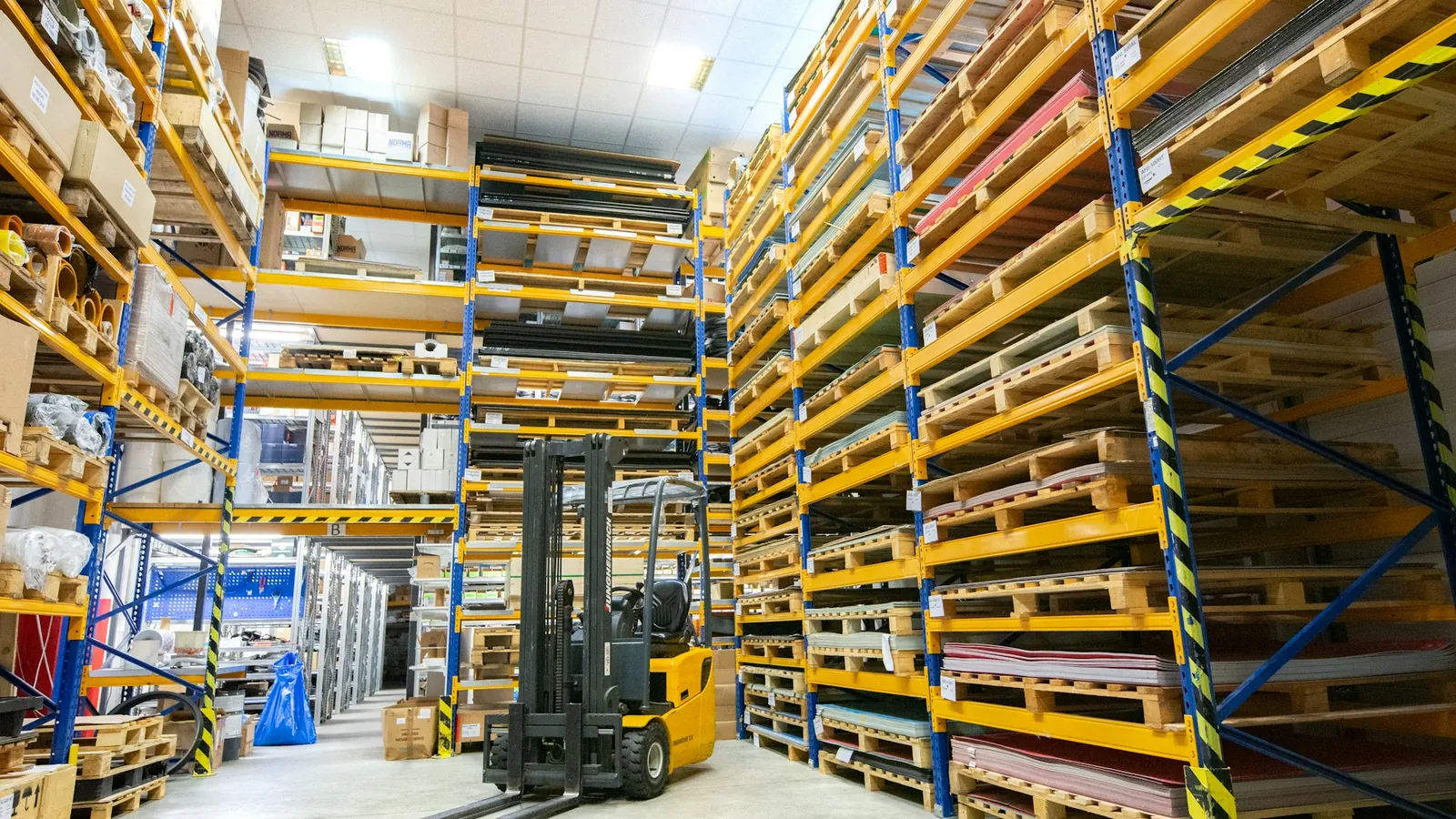 A forklift between high warehouse shelves