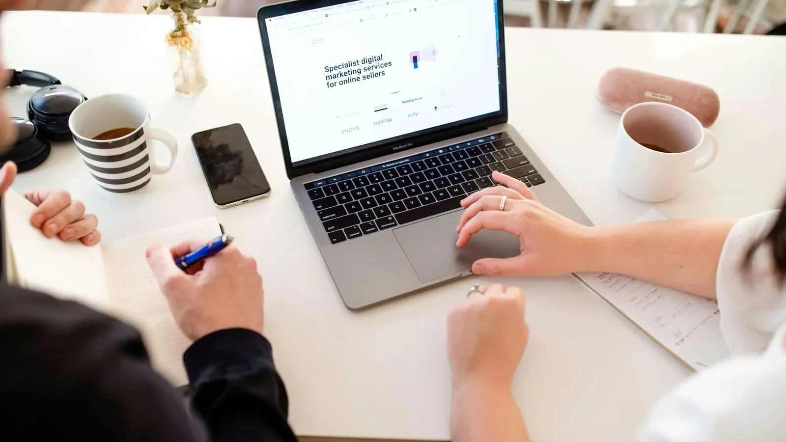Two people working on a laptop at a white table