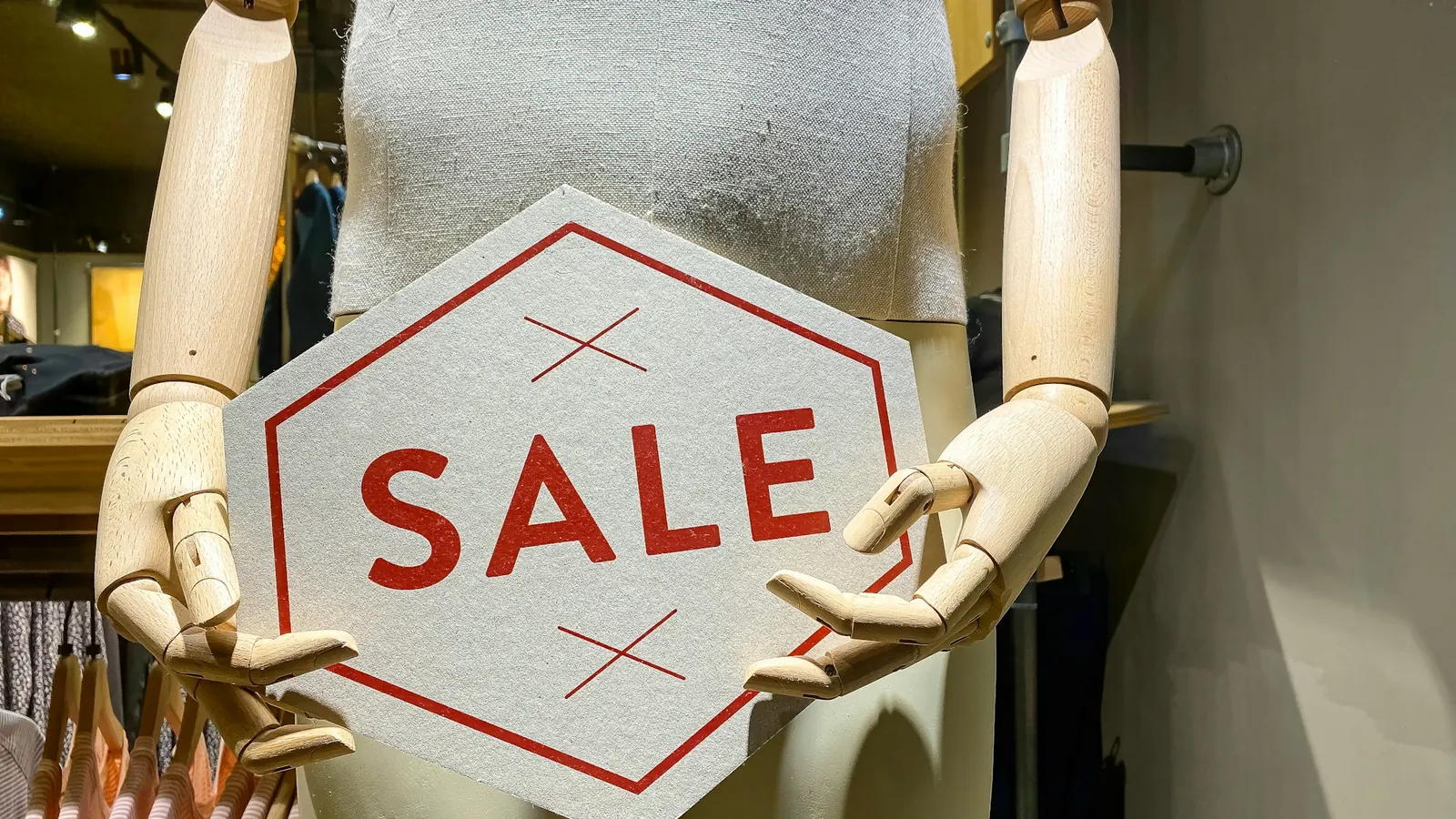 A mannequin holding a SALE sign in a shop