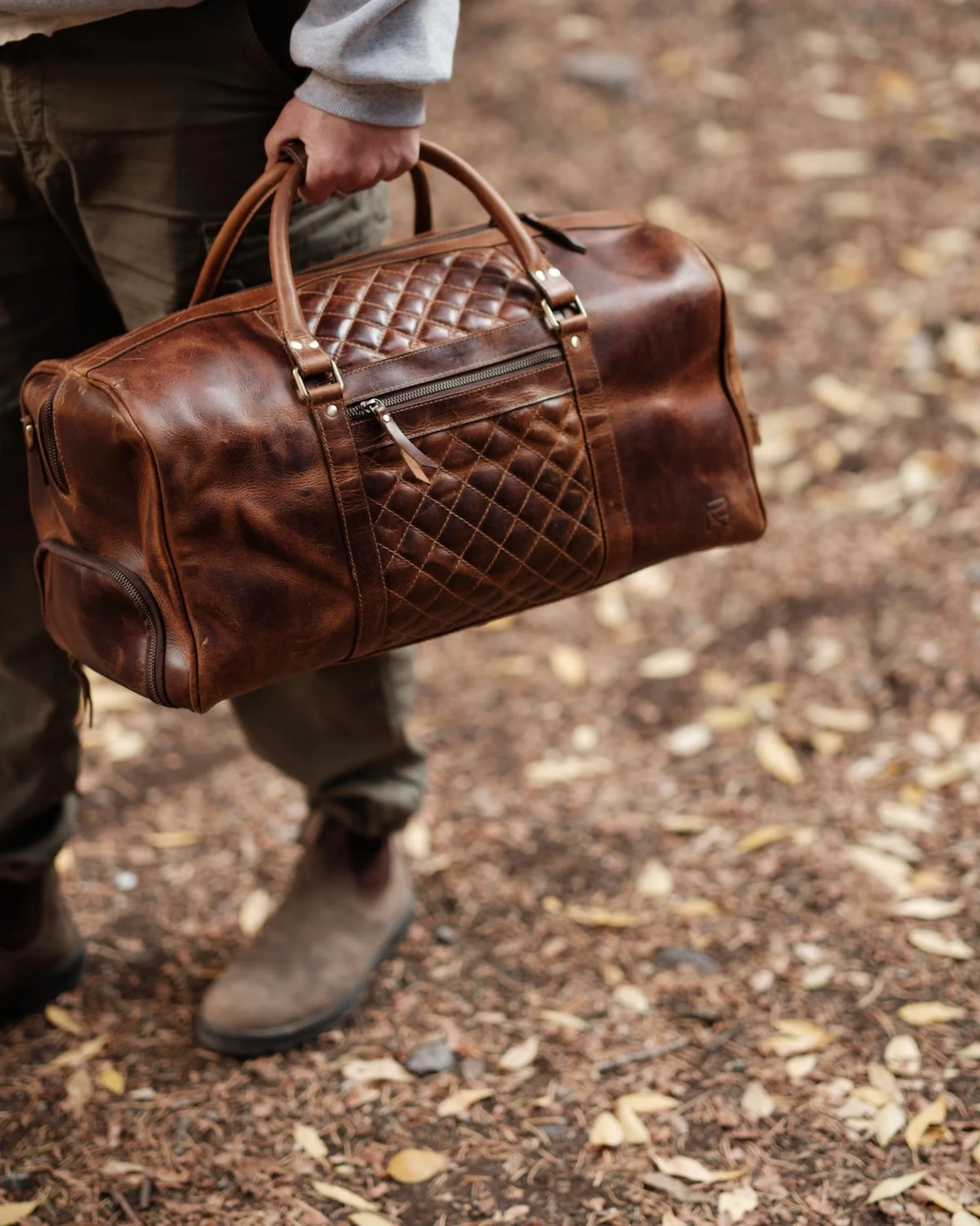 Quilted brown leather weekender duffel carried outdoors