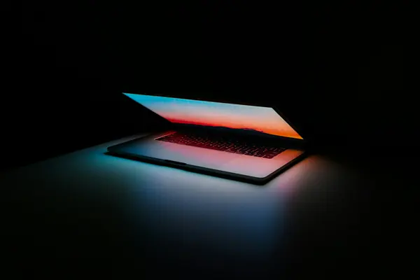 Laptop glowing on a dark desk