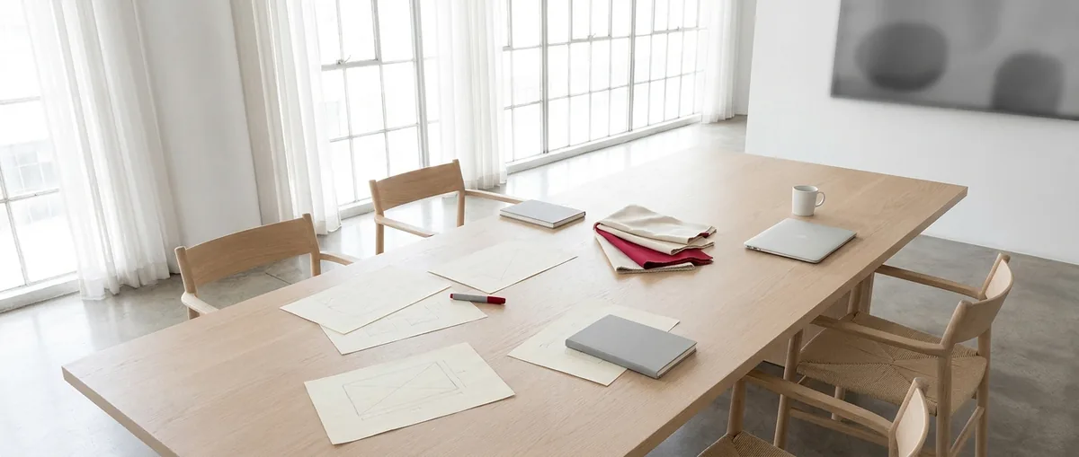 Agency studio table laid out with storefront wireframe sketches, fabric swatches and a laptop before a project kickoff